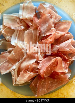 Coupes de savoureux prosciutto crudo italien typique et salami appelé finocchiona dans une plaque bleue. Salami traditionnel de la cuisine italienne. Directement au-dessus. Banque D'Images