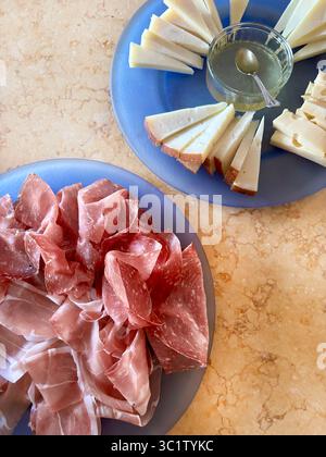 Coupes de savoureux prosciutto italien typique, salami et fromage dans des assiettes bleues sur la table. Cuisine italienne traditionnelle. Directement au-dessus. Banque D'Images