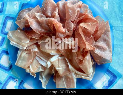Coupes de savoureux prosciutto crudo italien typique et salami appelé finocchiona dans une plaque bleue. Salami traditionnel de la cuisine italienne. Directement au-dessus. Banque D'Images