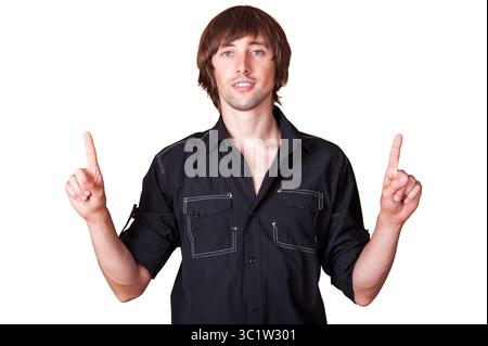 Un jeune homme décontracté dirige l'attention vers le haut avec les deux mains levées, souriant doucement. Banque D'Images