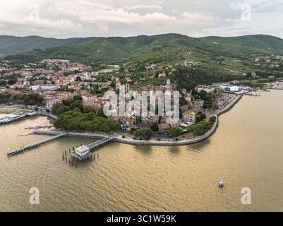 Vue aérienne de l'ancienne ville serrée par le lac Trasimeno, avec ses toits de tuiles rouges contrastant avec les collines verdoyantes, Passignano sul Trasimeno, Ombrie, Italie. Banque D'Images