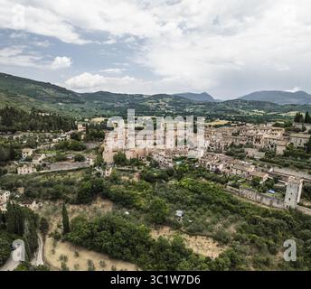 Vue aérienne d'une charmante ville médiévale nichée au milieu de collines verdoyantes sous un vaste ciel, Spello, Ombrie, Italie. Banque D'Images