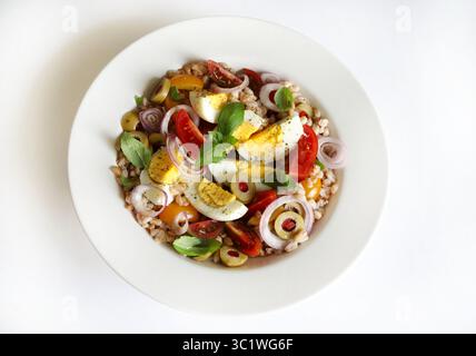 Salade épeinte maison avec œufs durs, légumes frais et basilic sur fond blanc. Salade d'épeautre. Nourriture saine. Directement au-dessus. Banque D'Images
