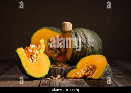 Citrouille verte fraîche avec centre orange vif repose sur la planche à découper à côté du couteau. Style culinaire de Thanksgiving ou d'Halloween dans un cadre d'automne confortable Banque D'Images