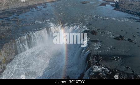 La puissante cascade de Selfoss capturée d'en haut présente un arc-en-ciel époustouflant qui vole au-dessus de l'eau rugissante. Cette vue à couper le souffle près de Selfoss est une véritable merveille naturelle. Banque D'Images