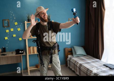 Jeune homme barbu voyageur enregistrant une vidéo sur une petite caméra prête pour la randonnée à la maison. concept de voyage backpacker Banque D'Images