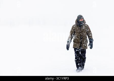 Yamalo Nenets, Russie - 16 avril 2021 : vue d'un personnage solitaire bravant le blizzard féroce, leurs vêtements sombres contrastent fortement avec l'immense étendue blanche de neige. Banque D'Images