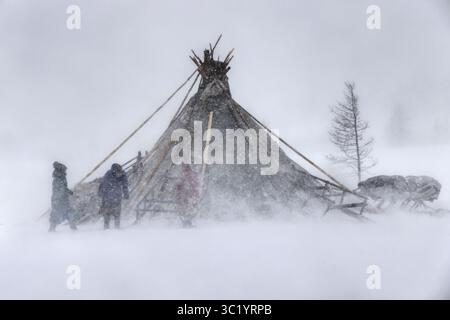 Yamalo Nenets, Russie - 16 avril 2021 : vue d'une tente traditionnelle du CHUM combattant la tempête de neige féroce, se fondant dans le paysage blanc sombre avec des personnages bravant les éléments. Banque D'Images