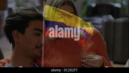 Couple penché portant un haut décontracté, pull en tricot orange sur un canapé moelleux dans le salon, tenant une tasse en céramique Banque D'Images