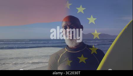 Homme debout portant une combinaison tenant une planche de surf jaune sur le rivage, avec superposition d'étoiles européennes Banque D'Images