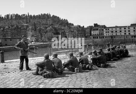La libération de Honfleur, Normandie, France pendant la seconde guerre mondiale. 26 août 1944. Un combattant de résistance français garde de jeunes soldats allemands après leur capitulation. Banque D'Images