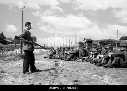 La libération de Honfleur, Normandie, France pendant la seconde guerre mondiale. 26 août 1944. Un combattant de résistance français garde de jeunes soldats allemands après leur capitulation. Banque D'Images