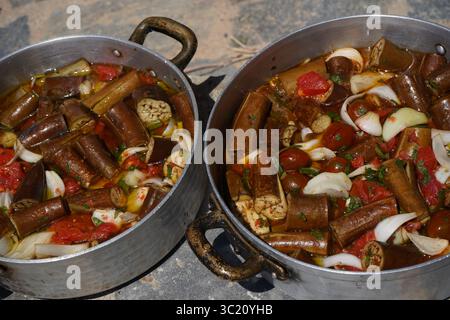 Vue de haut en bas de « melitzanes giaxni » non cuites, une recette grecque traditionnelle avec aubergines, tomates, oignons et huile d’olive, disposées dans deux plateaux métalliques. Banque D'Images