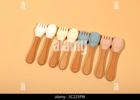 Ensemble de cuillères et fourchettes en silicone colorées pour bébé avec poignées en bois Banque D'Images