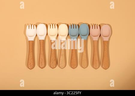 Ensemble de cuillères et fourchettes en silicone colorées pour bébé avec poignées en bois Banque D'Images