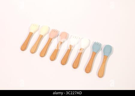 Ensemble de cuillères et fourchettes en silicone colorées pour bébé avec poignées en bois Banque D'Images
