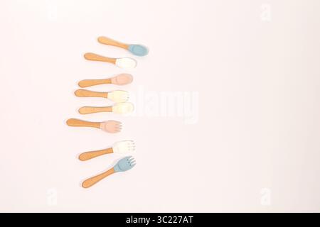 Ensemble de cuillères et fourchettes en silicone colorées pour bébé avec poignées en bois Banque D'Images