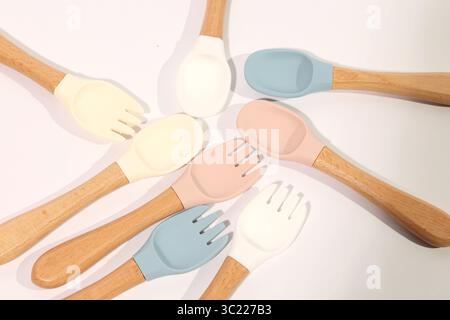 Ensemble de cuillères et fourchettes en silicone colorées pour bébé avec poignées en bois Banque D'Images