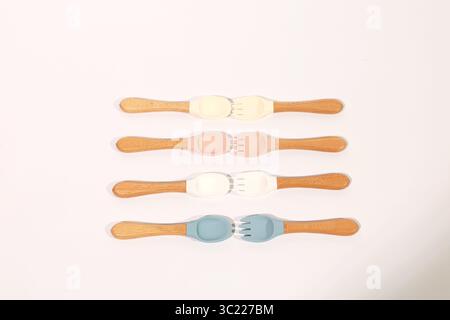 Ensemble de cuillères et fourchettes en silicone colorées pour bébé avec poignées en bois Banque D'Images