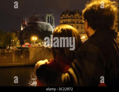 16 avril 2019 - Paris, France - les résidents regardent les pompiers se battre pour éteindre un incendie géant qui a englouti la cathédrale notre-Dame. Le président français Macron a promis de reconstruire le bâtiment du XIIIe siècle qui accueille des dizaines de millions de fidèles et de touristes chaque année. (Crédit image : © Judith White/ZUMA Wire) Banque D'Images