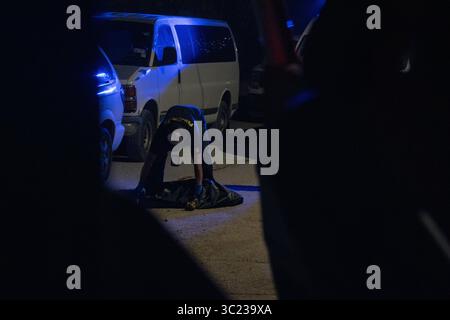 Un fonctionnaire enquête sur une scène de crime sous les feux d'un véhicule à Ciudad Juarez. Banque D'Images