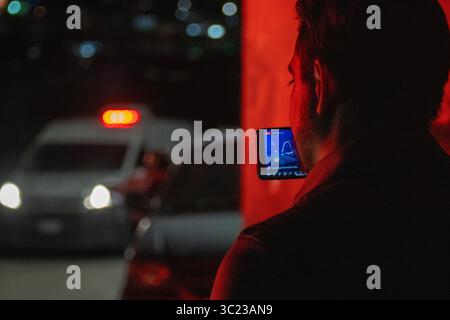 L'homme utilise un smartphone dans la voiture, Ciudad Juarez, sous la lueur des lampadaires au milieu de la violence urbaine croissante. Banque D'Images