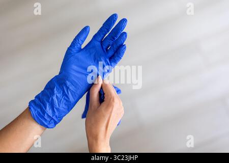 Personne portant des gants de protection bleus. Gros plan des mains portant des gants jetables bleus, représentant l'hygiène, la sécurité médicale ou la protection Banque D'Images