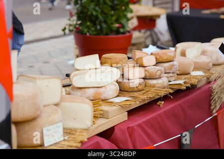 Assortiment de fromages sur un étal rustique avec tapis de paille et nappe rouge Banque D'Images