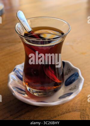 Une présentation classique du thé turc servi dans un verre en forme de tulipe, symbolisant la chaleur et l'hospitalité de la culture turque. Cette image capture t Banque D'Images