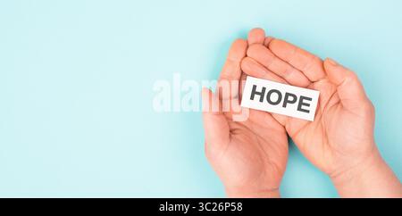Tenir le mot espoir dans les mains, croire et croire concept, avoir foi dans l'avenir, esprit positif d'espoir Banque D'Images