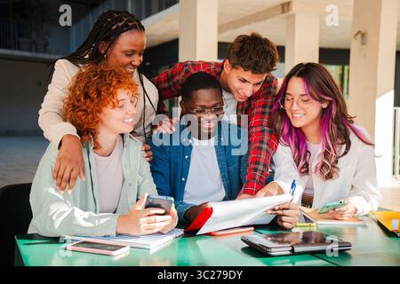 Un groupe diversifié d'étudiants ciblés collaborant activement à un projet académique passionnant avec des documents et des appareils, mettant en valeur le travail d'équipe et Banque D'Images