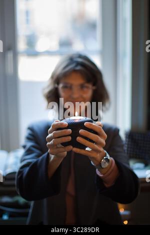 Belle femme hors foyer montrant la lumière de bougie vers la caméra. Lumière de bougie confortable sur la mise au point dans les mains des modèles faisant l'atmosphère chaude des vacances de Noël Banque D'Images