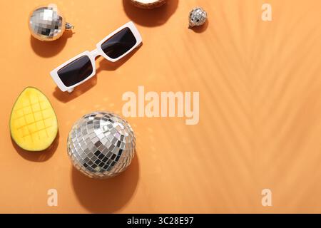Boules disco avec lunettes de soleil et mangue sur fond orange Banque D'Images
