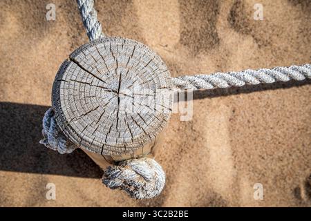 Poteau en bois avec corde nautique sur Sandy Beach, vue de haut en bas de détail côtier.. Banque D'Images