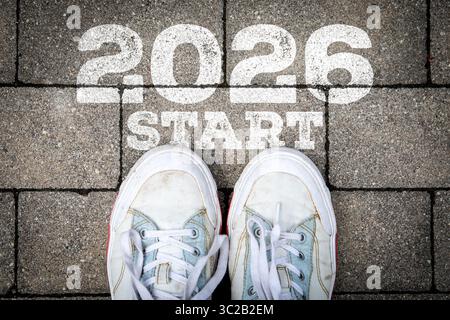Nouvelle année 2026 Start concept avec des baskets sur la chaussée et peint message de motivation. Banque D'Images
