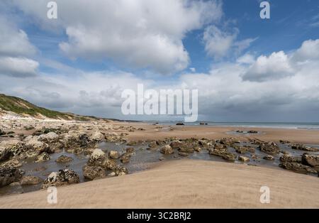 La marée basse à Speeton Sands révèle une plage rocheuse souvent déserte. Photographie prise en regardant vers le nord en direction de Filey à plusieurs kilomètres de là. Banque D'Images