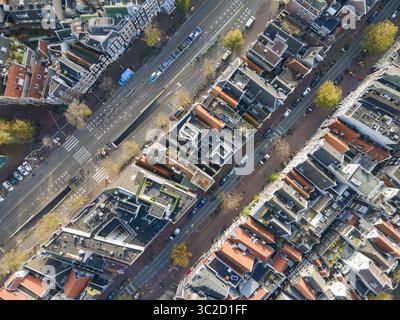 Vue aérienne des rangées de bâtiments soignés d'une ville avec des toits rouges et des rues étroites, avec une avenue centrale coupant à travers le tissu urbain, Amsterdam, Hollande du Nord, pays-Bas. Banque D'Images