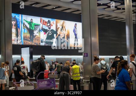 Londres, Angleterre. Aéroport d'Heathrow. Terminal cinq. Publicité Burberry pendant Glastonbury à la récupération des bagages. Banque D'Images