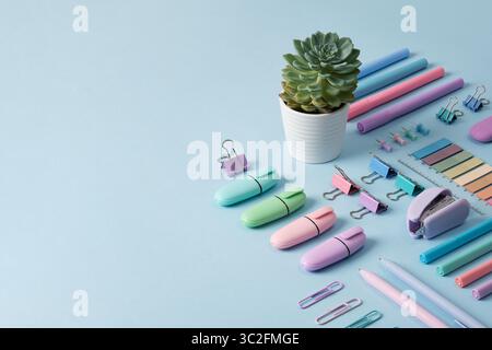 Bannière de papeterie avec des fournitures de bureau de couleur pastel soigneusement disposées sur fond bleu clair. Place pour votre texte. Banque D'Images