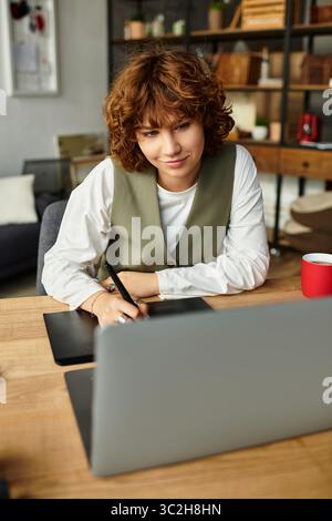 Une jeune femme aux cheveux bouclés travaille avec diligence sur son ordinateur portable, équilibrant créativité et productivité. Banque D'Images