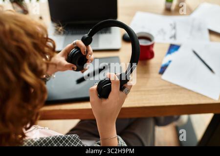 Jeune femme aux cheveux bouclés travaille avec diligence depuis son appartement confortable, profitant de la freelance à distance. Banque D'Images