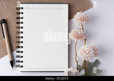 Vue de dessus du bloc-notes vierge avec fleur et stylo Banque D'Images