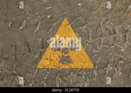 Panneau radioactif orange au sol avec traces de pneus, vue de dessus. Pollution radiologique Banque D'Images