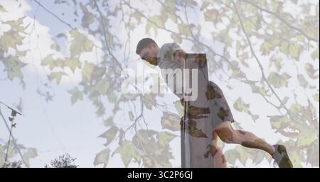 Exécutant Dips homme portant des vêtements de sport sur des barres parallèles au parc extérieur avec des branches d'arbres, des feuilles. Athlétique, force, endurance, nature, extérieur, fi Banque D'Images