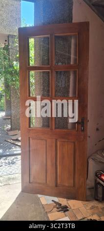 Une riche porte en bois vintage brun avec six vitres est présentée à l'extérieur, probablement lors d'un projet de rénovation ou de remplacement de la maison, mettant l'accent sur Rusti Banque D'Images