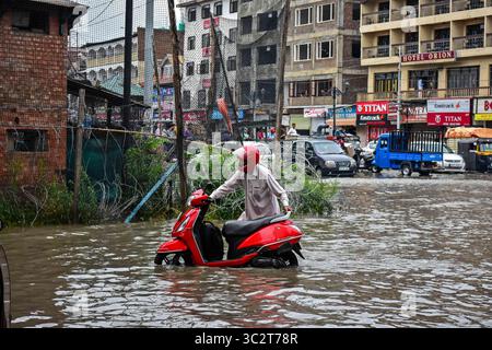 1er août 2019, Srinagar, J&K, Inde : un homme pousse son scooter à travers une route goudronnée d'eau après les fortes pluies à Srinagar..les pluies ont causé un goudronnage dans de nombreuses zones de Srinagar exposant le mauvais système de drainage de la ville. Le département météorologique a prédit de fortes précipitations pour les prochains jours dans toute la région. (Crédit image : © Saqib Majeed/SOPA images via ZUMA Wire) Banque D'Images