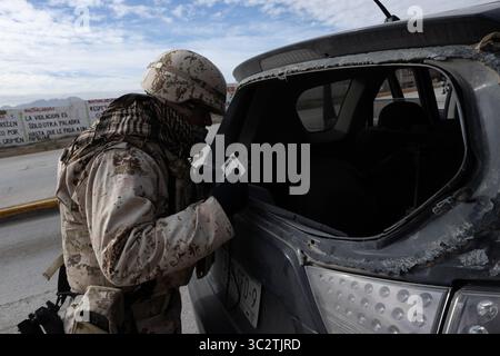 Soldat inspecte un véhicule endommagé à Ciudad Juarez, sur fond de slogans anti-violence. Banque D'Images