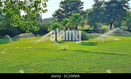 Système d'irrigation automatique pour une pelouse verte sur le territoire d'un hôtel grec par une chaude journée d'été Banque D'Images