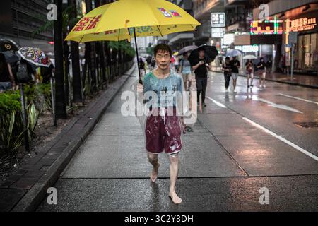 Août 18, 2019, Hong Kong, Hong Kong SAR, Chine : un homme marche pieds nus tenant un parapluie jaune lors de la manifestation..toke protestataires dans la rue sur un dimanche pluvieux dans une manifestation pro-démocratie sur l'île de Hong Kong, ils exigent le retrait complet de la loi sur l'extradition et le gouvernement à mettre en place une enquête indépendante sur les récents affrontements entre manifestants et policiers - Les organisateurs ont déclaré que c'était le plus grand rassemblement au cours de la semaine. (Crédit Image : © Ivan Abreu/SOPA des images à l'aide de Zuma sur le fil) Banque D'Images