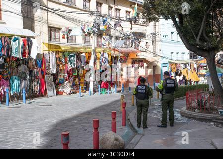 Une rue colorée à la Paz, la capitale de la Bolivie en Amérique du Sud. Deux membres de la police touristique se tiennent debout et regardent. Banque D'Images
